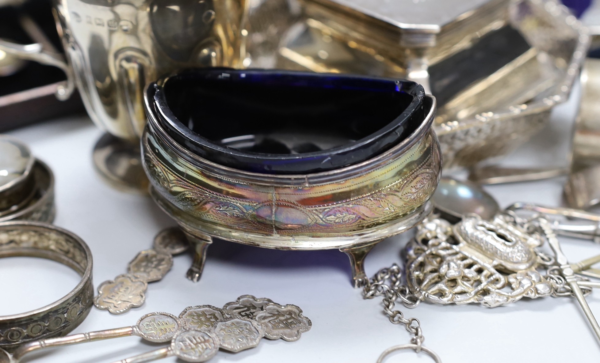 Assorted silver ware including two cased sets of six teaspoons, one with tongs, a christening mug, pierced sterling octagonal bowl, a Scottish silver quaich, inkwell, salt, three napkin rings, enamelled pill box, sifter